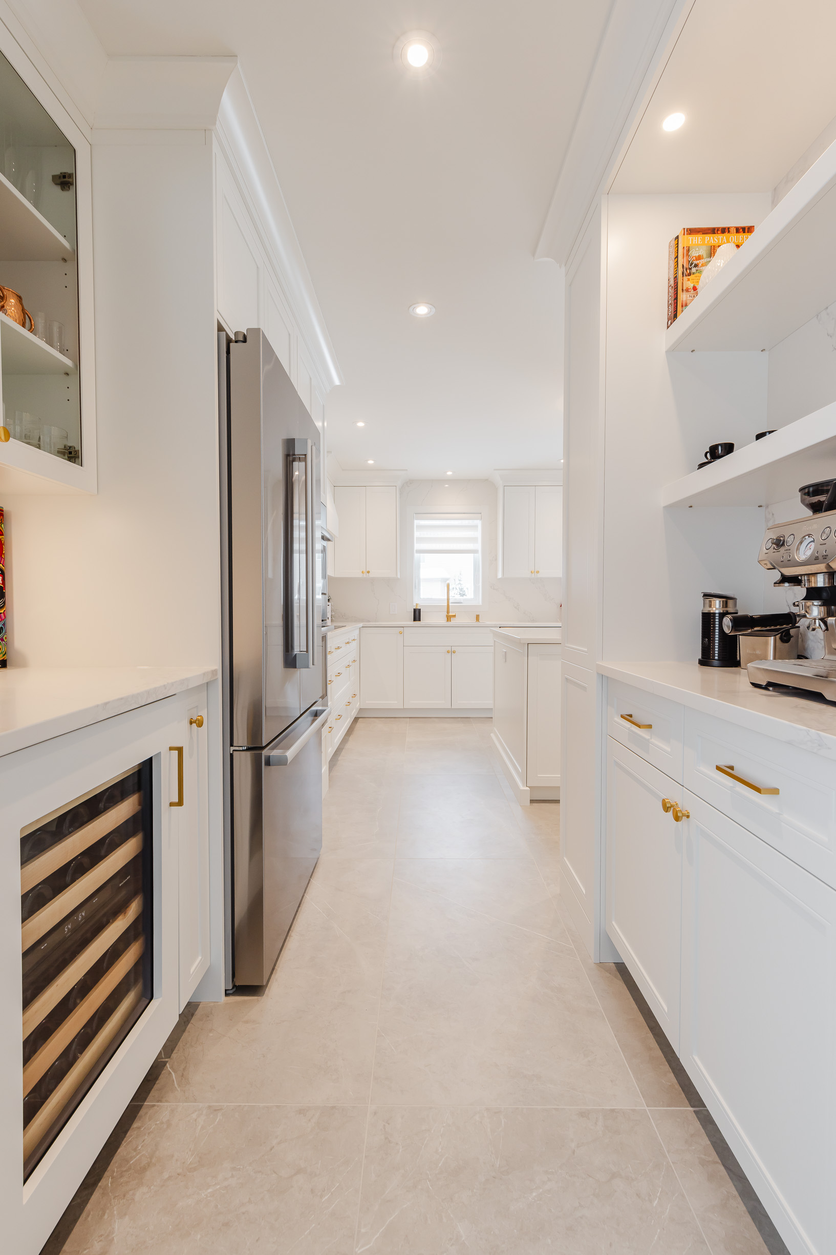 Stylish modern white kitchen with luxury wine cooler, stainless steel fridge, and elegant design elements.