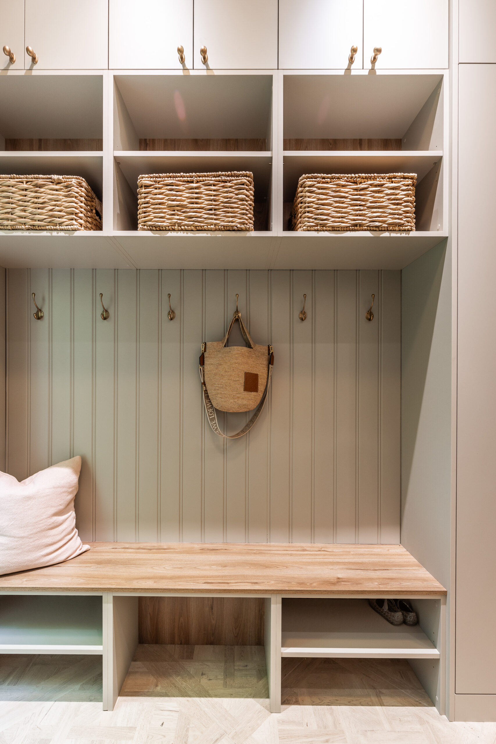Stylish mudroom featuring a wooden bench, woven baskets, and hooks, offering a cozy and organized entryway solution.