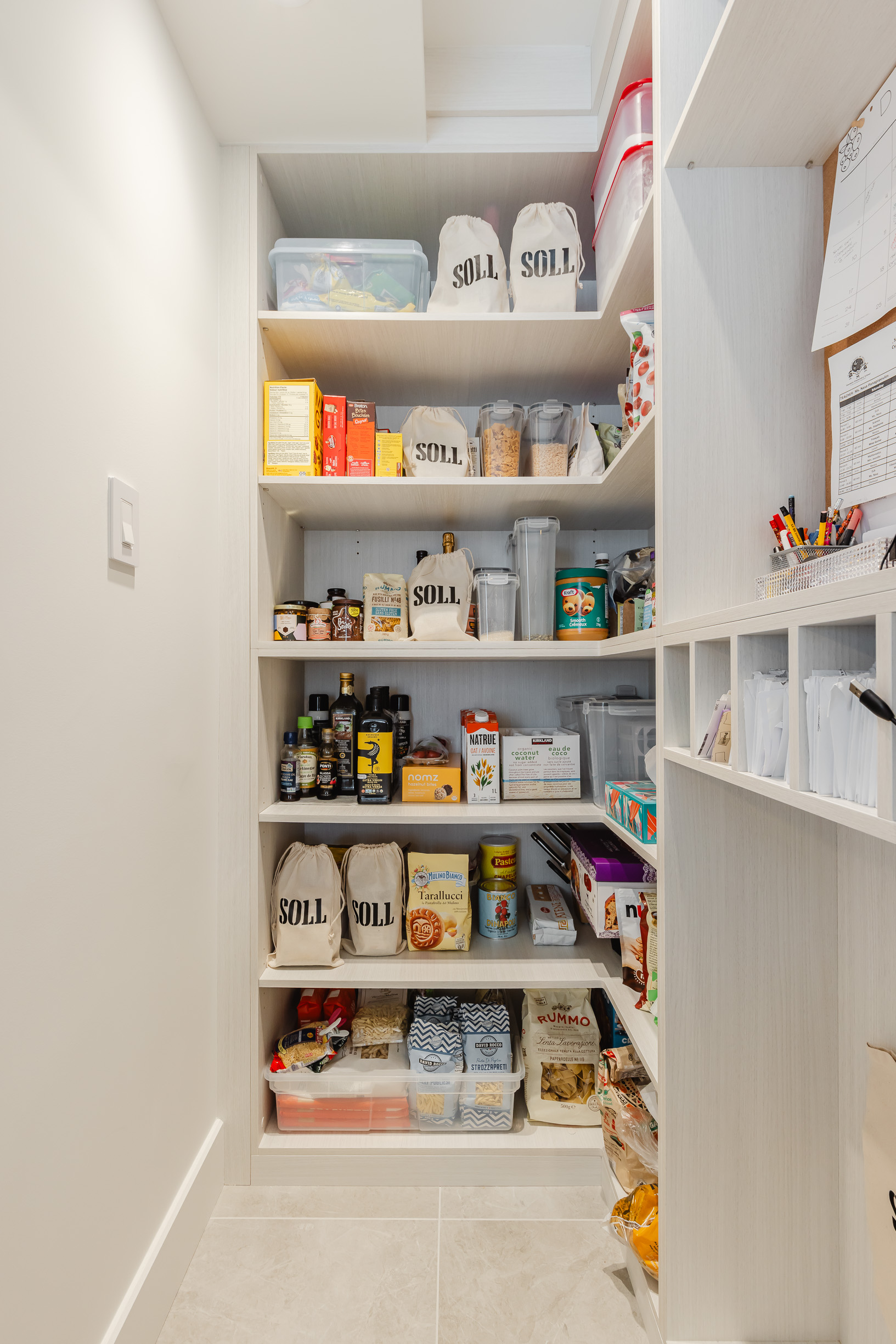 A bright and organized pantry features stylish white cabinetry and neatly arranged containers for efficient storage and easy access to essentials.