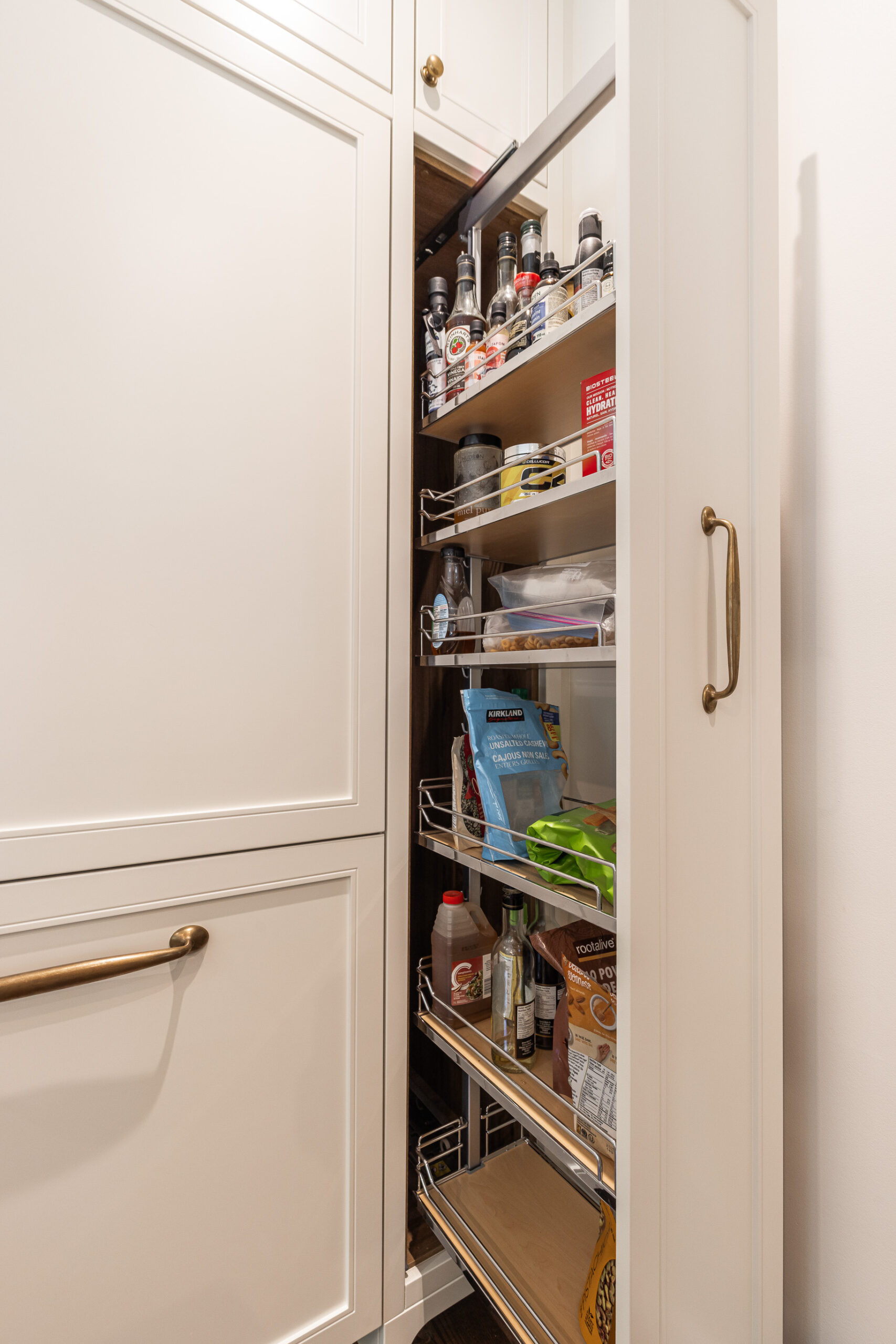 Sleek modern pantry with organized shelves for spices, snacks, and baking essentials in white cabinetry.