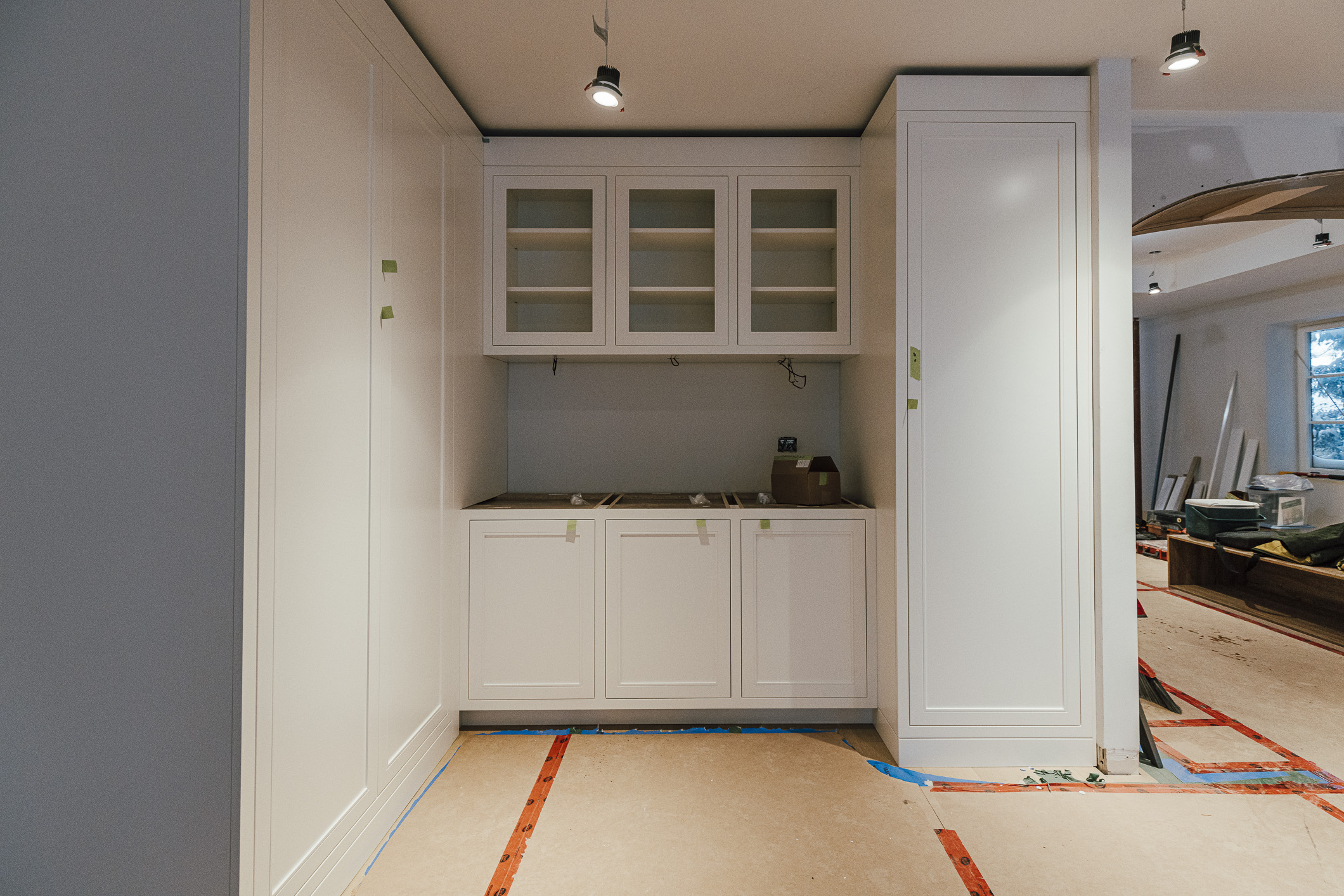 Ongoing kitchen renovation features sleek white cabinetry in a bright, unfinished space, showcasing its potential for a modern culinary oasis.