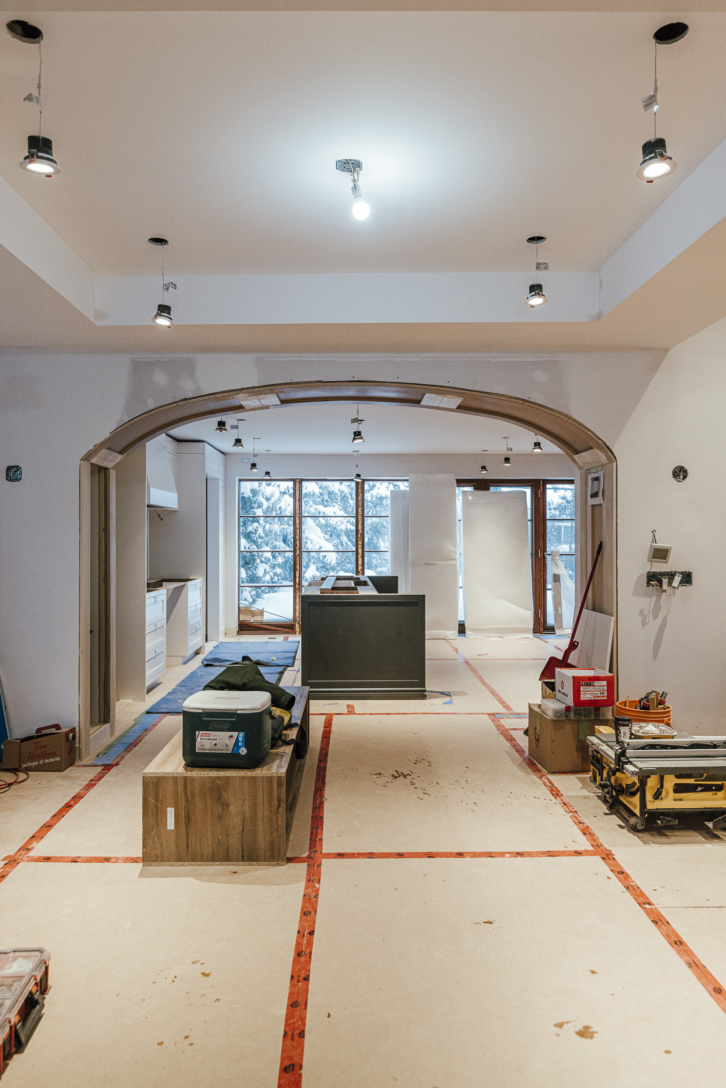 Bright interior space under renovation, featuring an elegant archway, natural light, and tools indicating a design transformation in progress.
