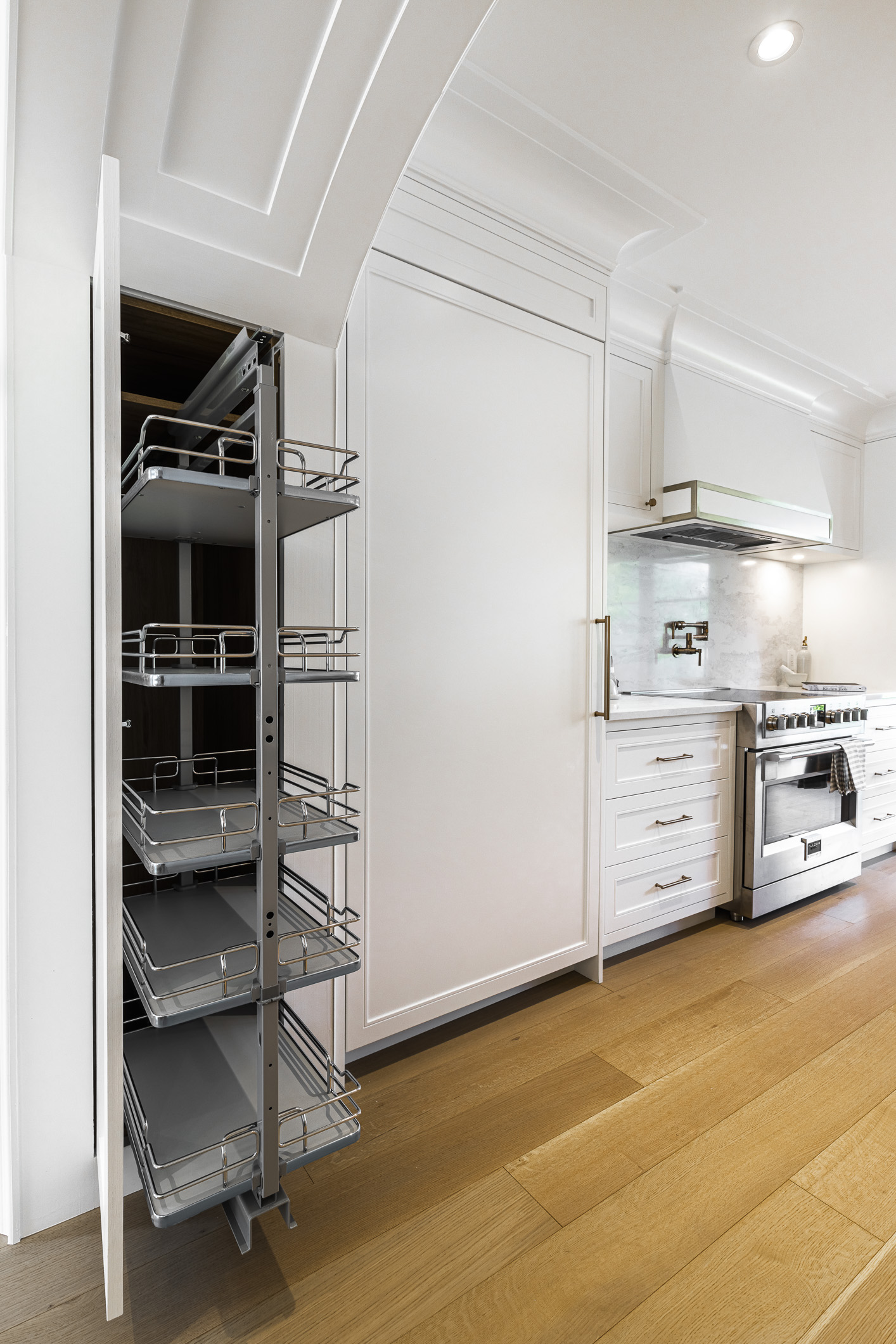 Discover a modern minimalist kitchen featuring sleek white cabinetry, a pull-out pantry, and stylish stainless steel appliances.