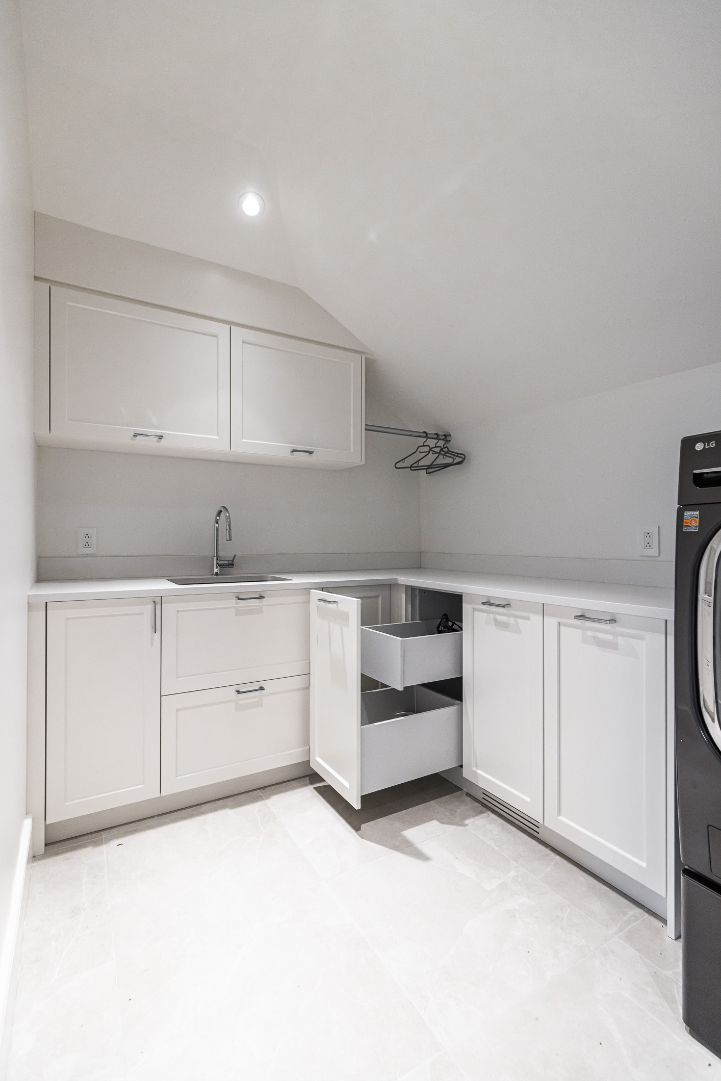 A modern minimalist kitchen features sleek white cabinetry, smart storage solutions, and a striking black refrigerator for balanced elegance.