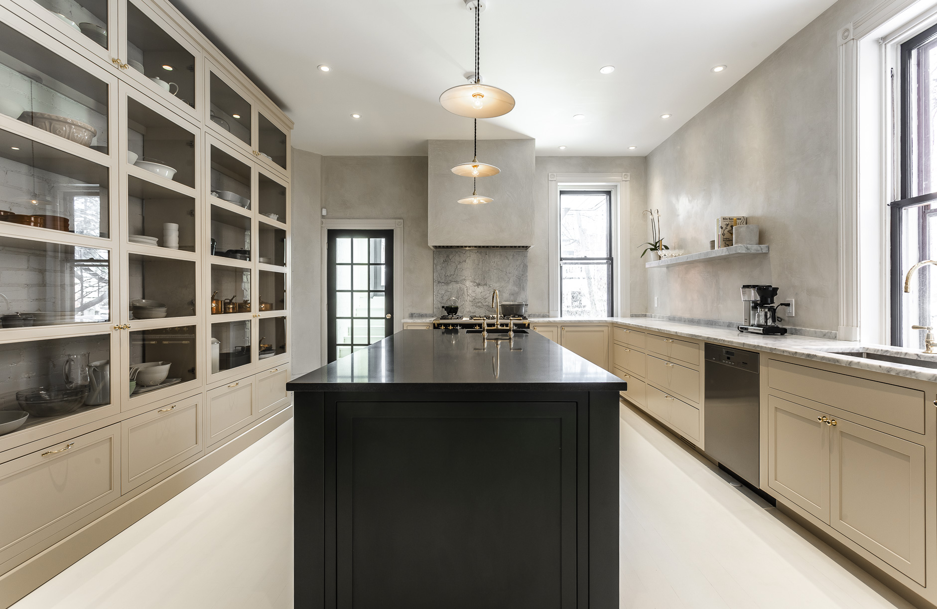 Elegant modern kitchen showcasing a warm beige palette, a bold black island, and abundant natural light for a stylish cooking space.