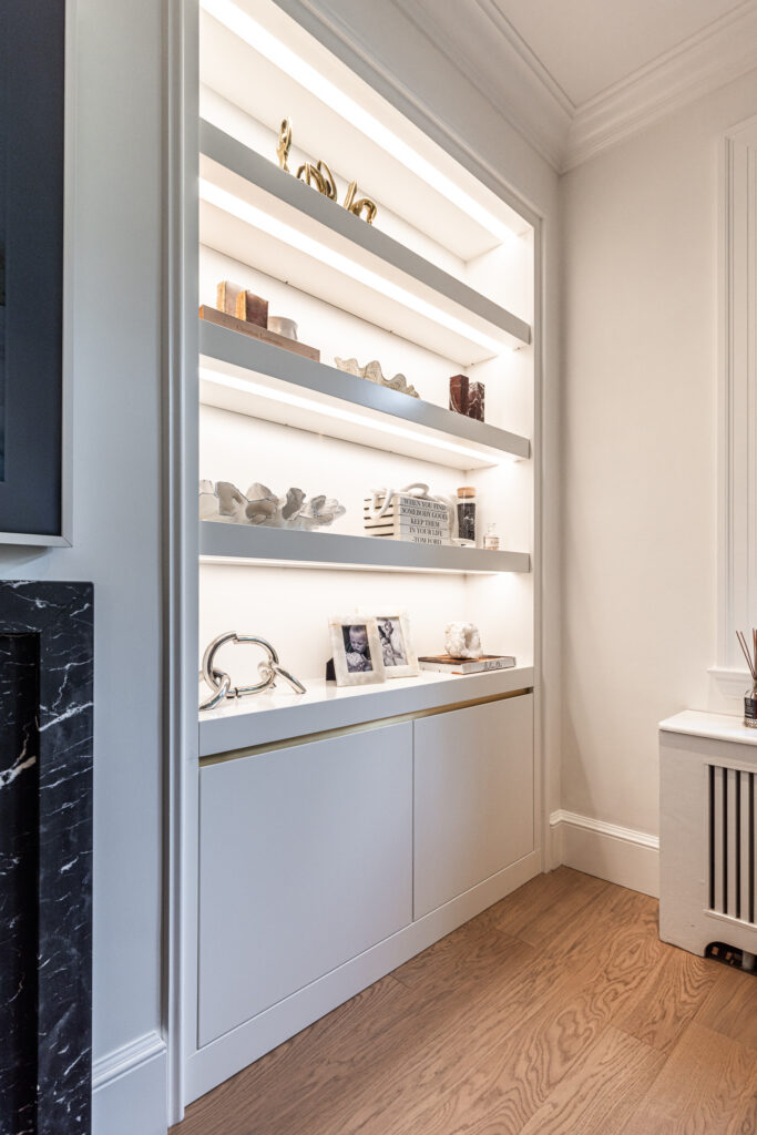 Elegant interior nook with backlit shelving, curated decor, and warm wooden floors.