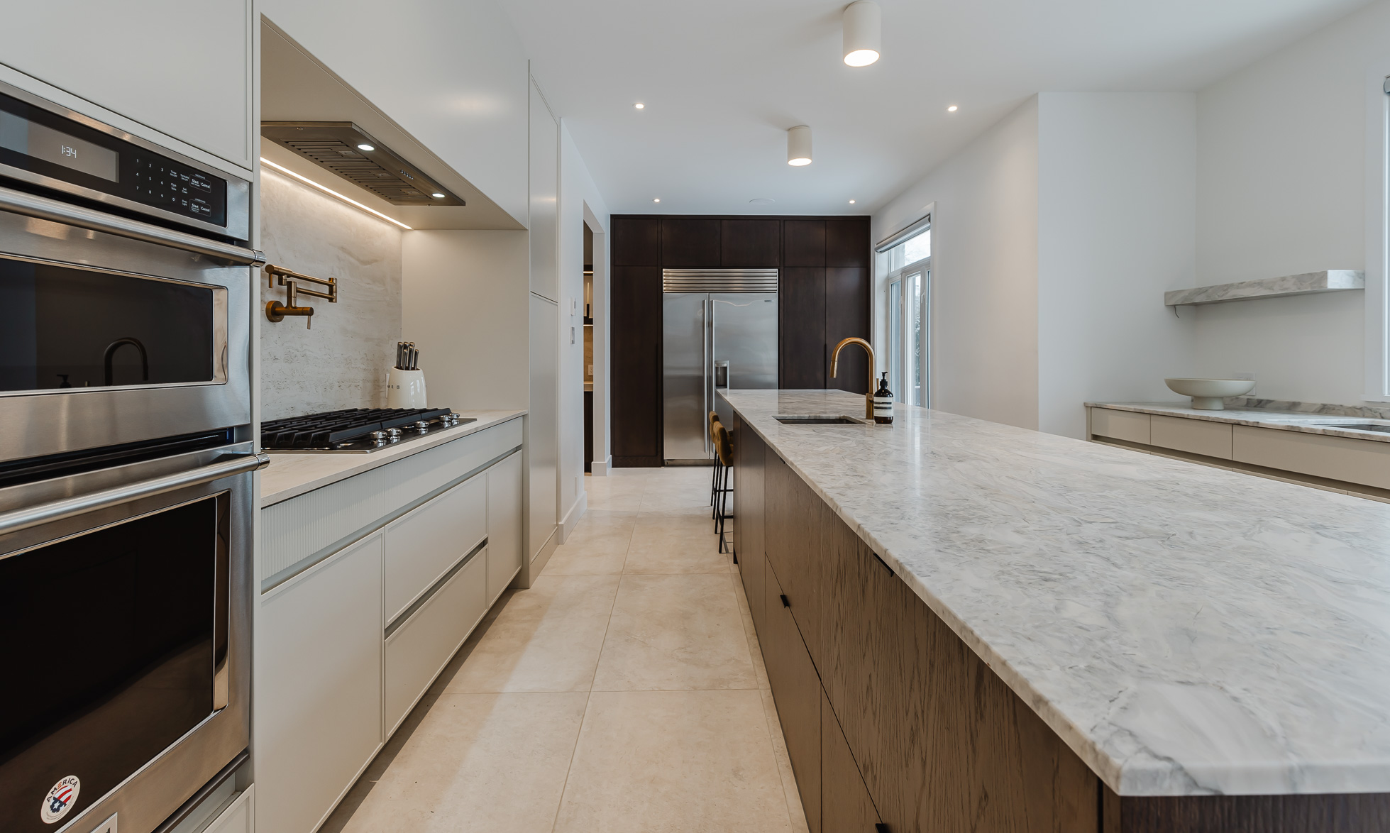 Elegant modern kitchen featuring a striking marble island, high-end appliances, and a blend of light and dark cabinetry for a harmonious design.