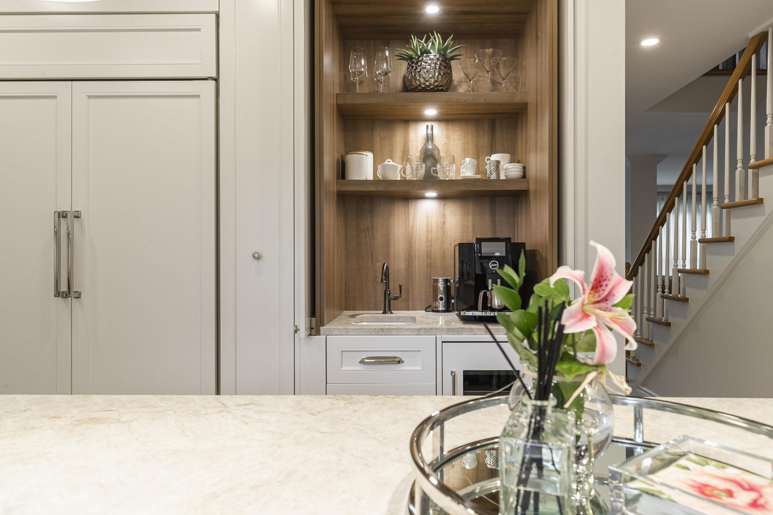 Sophisticated kitchen featuring light cabinetry, stylish decor, and fresh greenery, creating a warm and inviting space for gatherings.
