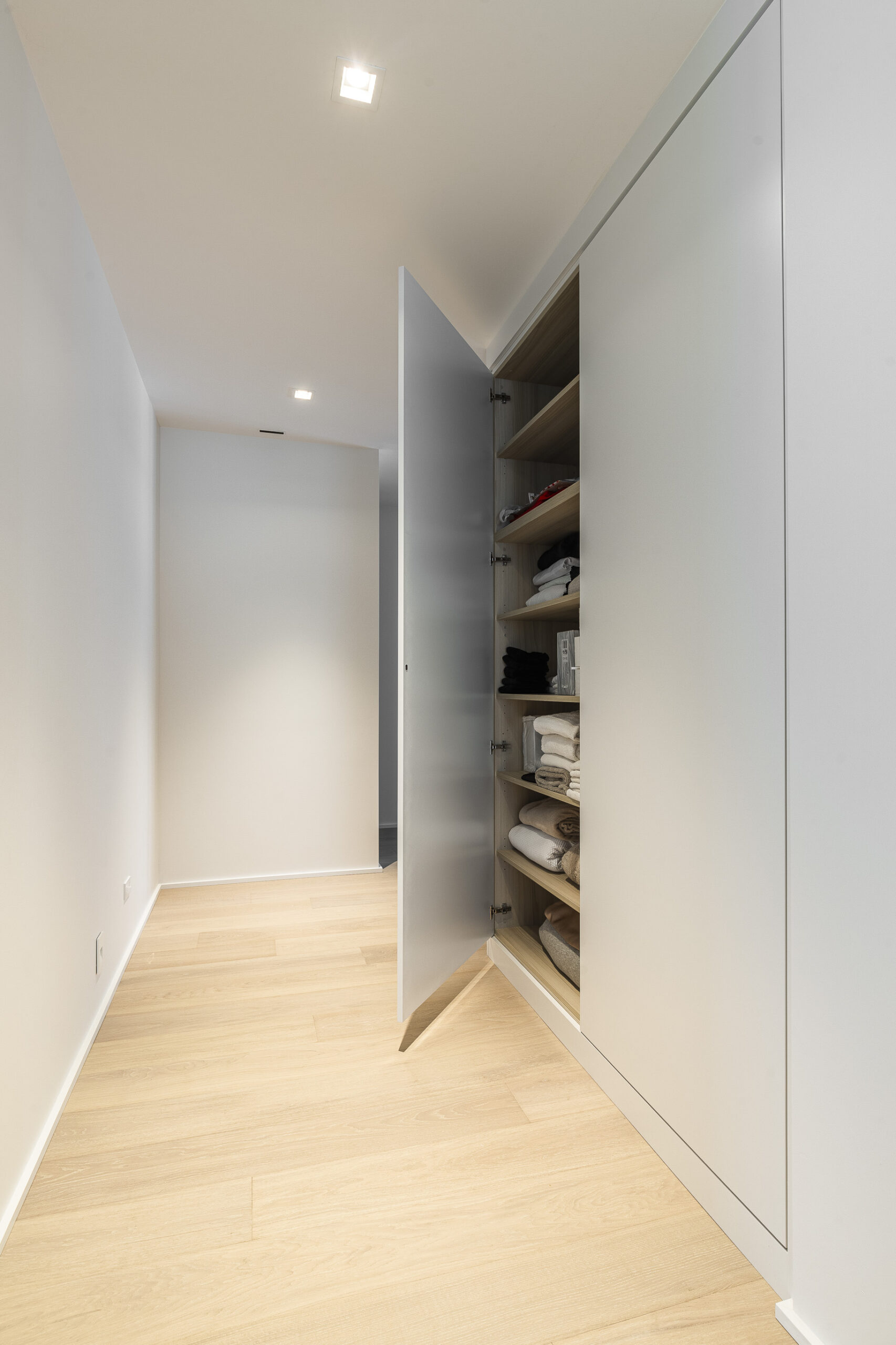 Modern interior featuring a sleek open cabinet and warm wood flooring, creating an organized and serene atmosphere.