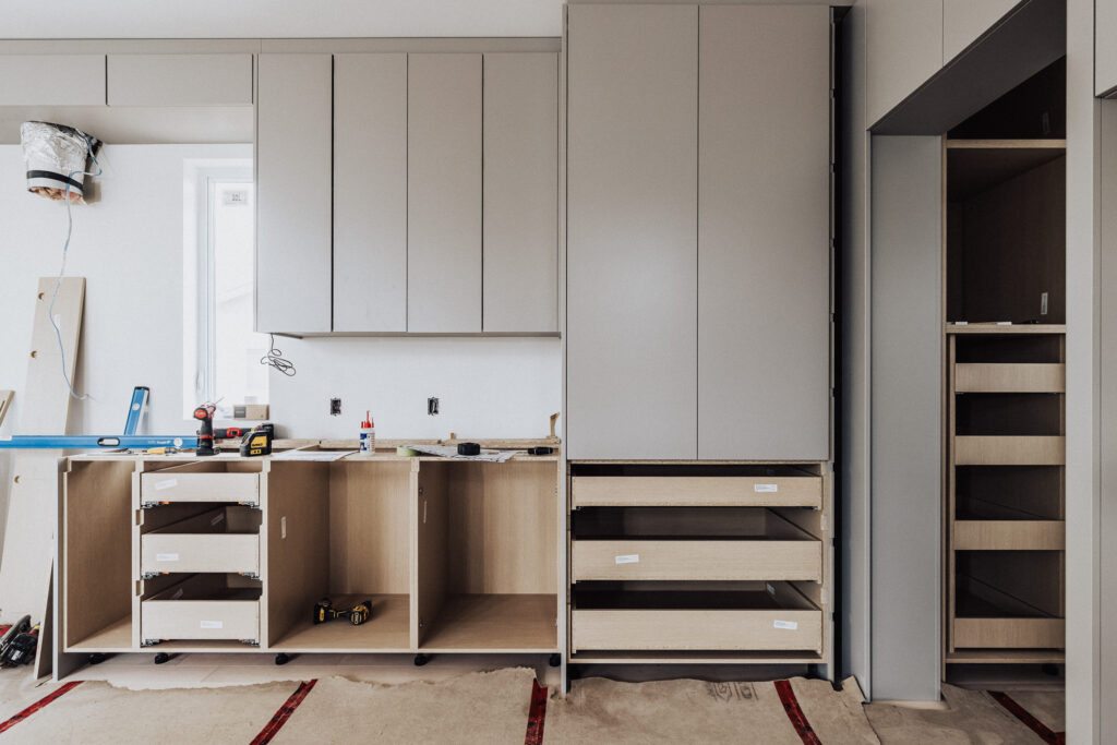 Modern kitchen renovation with sleek cabinetry and tools in an unfinished, light-filled space.