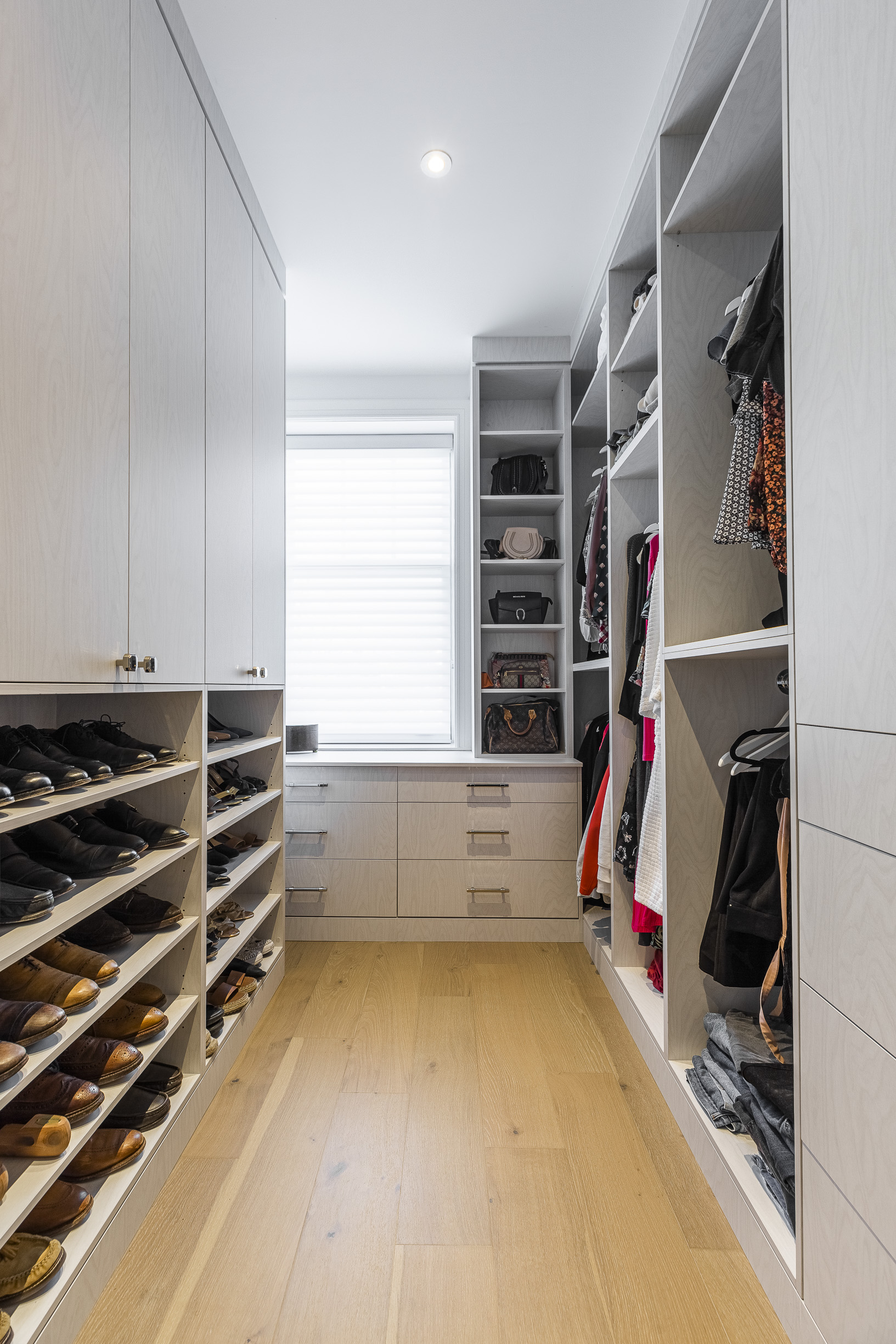 Experience modern elegance in this walk-in closet with organized shelving, vibrant clothing, and abundant natural light.