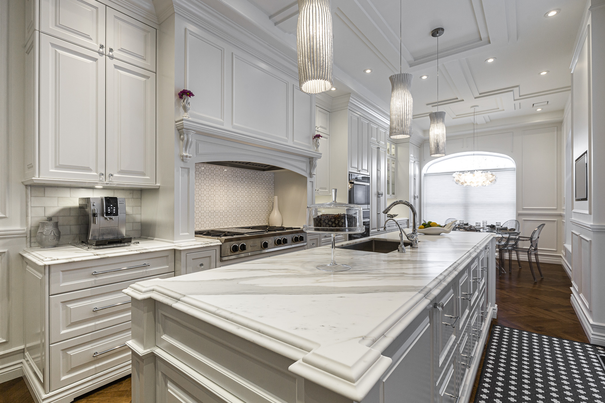 Discover a stunning white modern kitchen with a marble island, sleek appliances, and warm wooden flooring, perfect for culinary creations and gatherings.