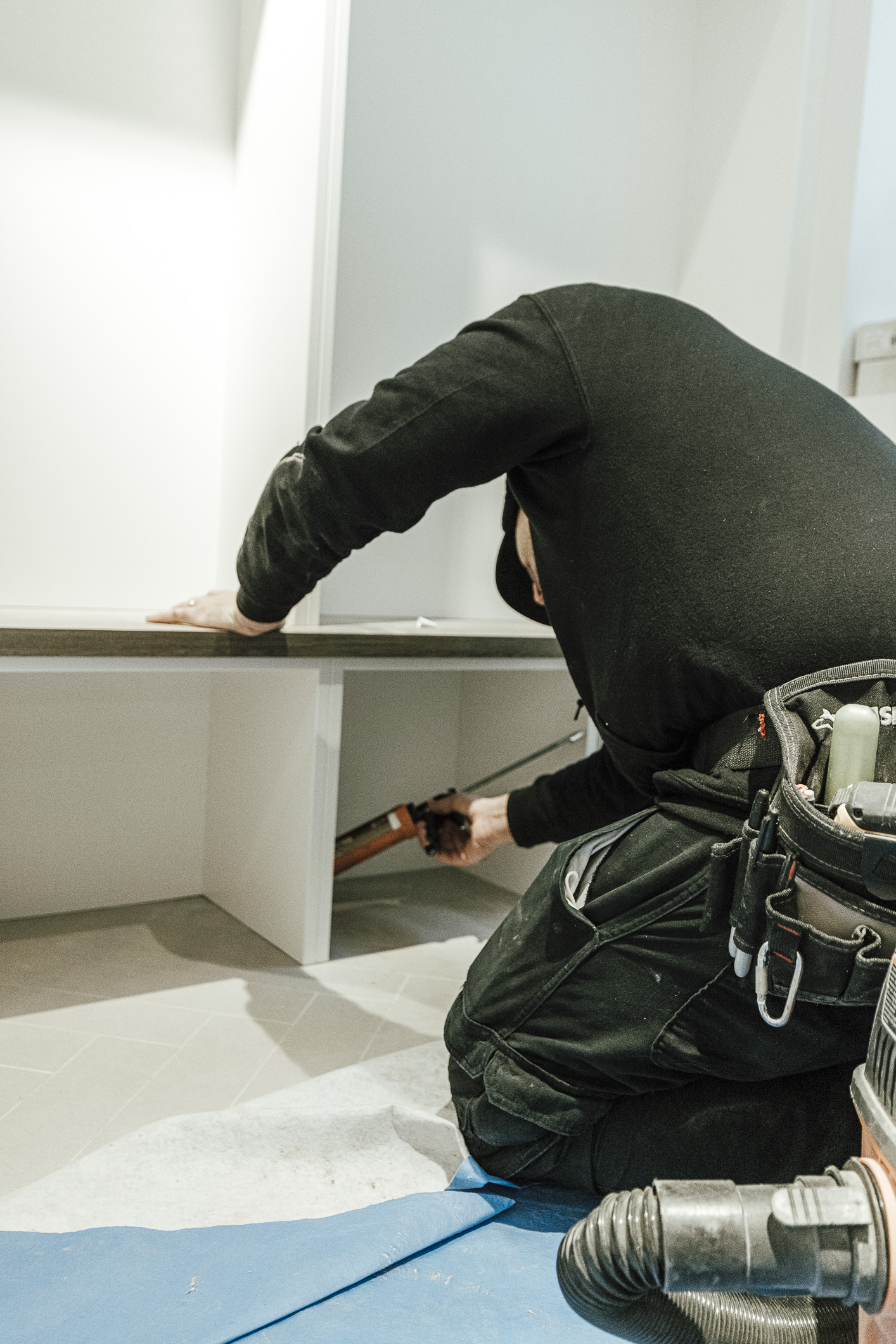 A skilled worker meticulously installs modern furniture, demonstrating professionalism and attention to detail in a clean, minimalist space.