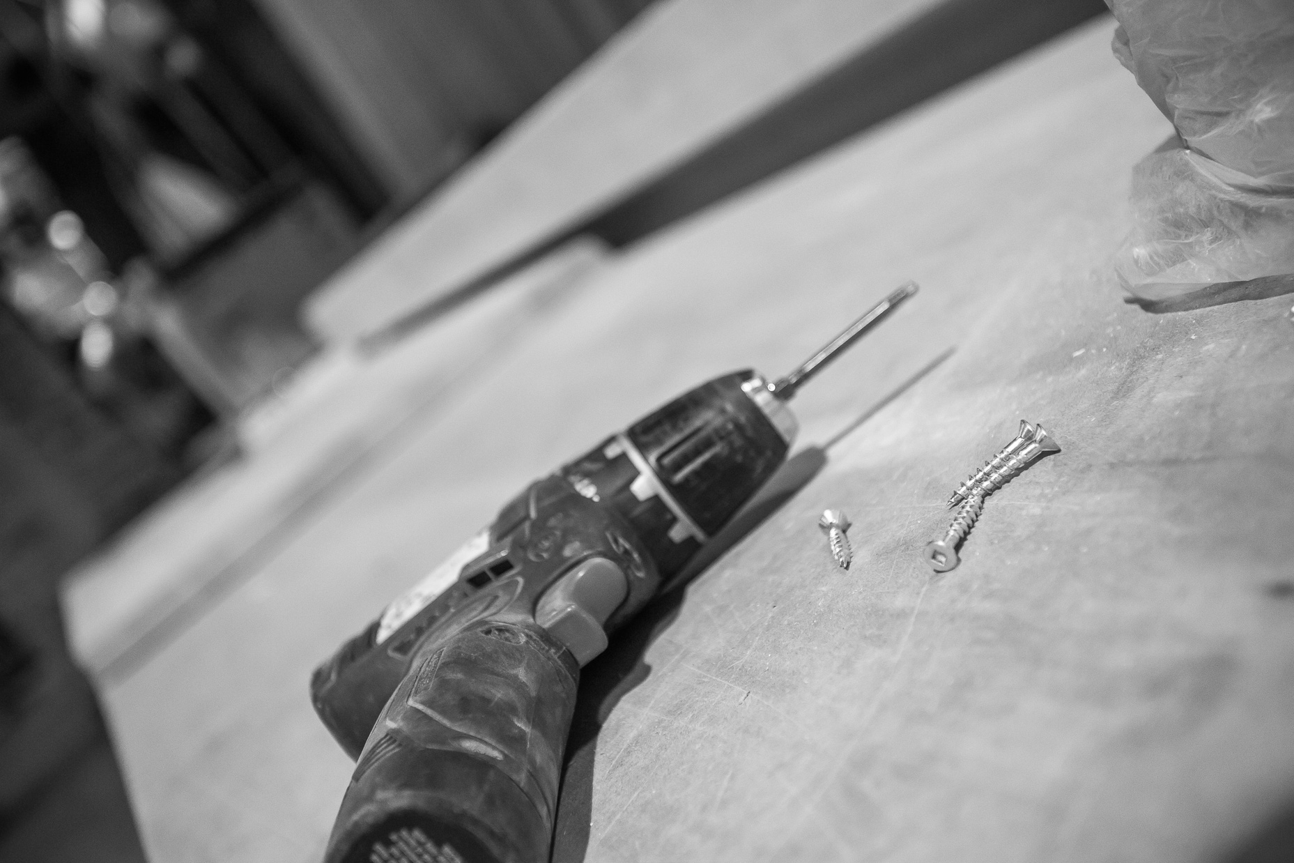 A well-used cordless drill and shiny screws rest on textured wood, ready for your next DIY project.