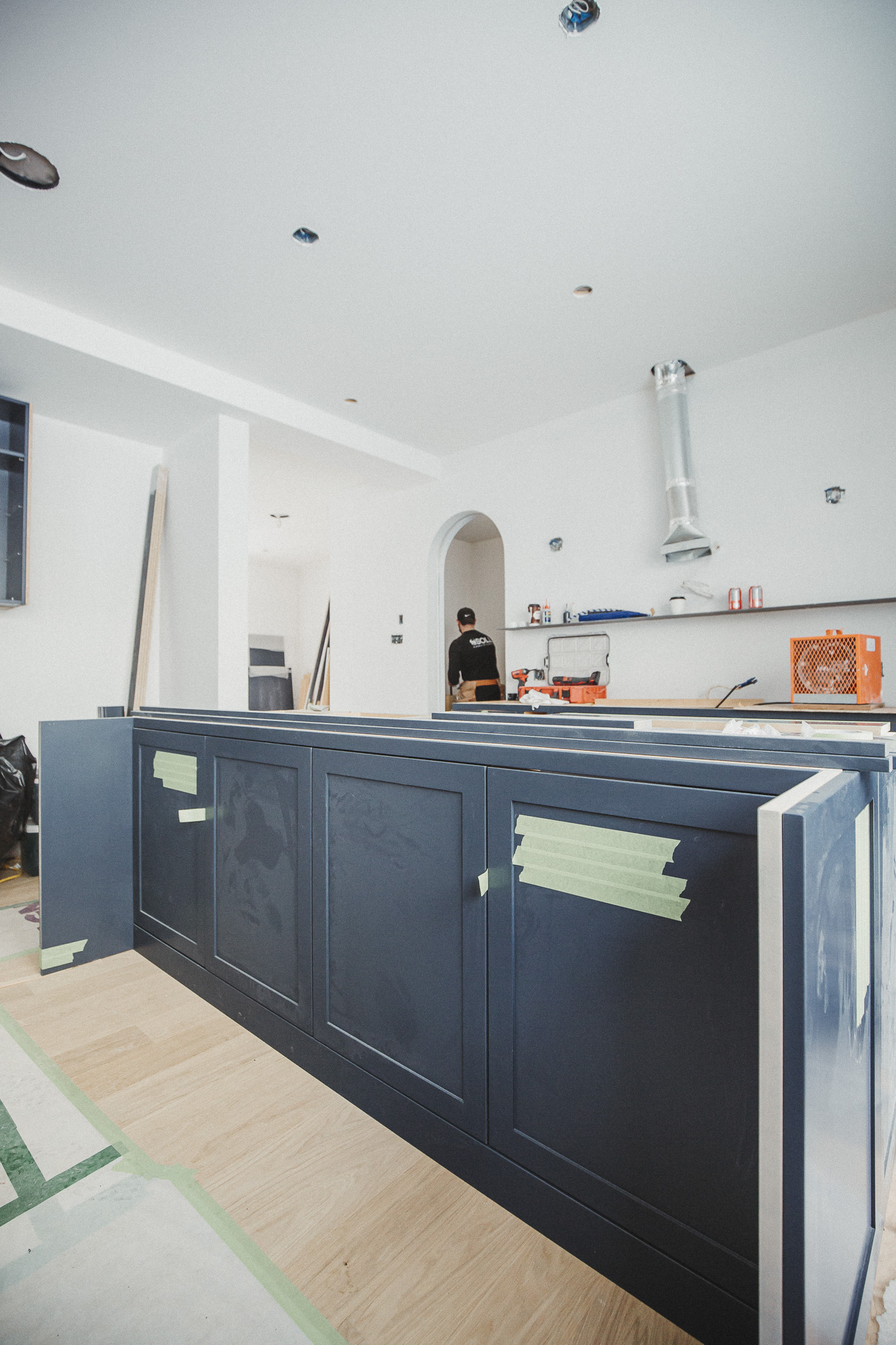 A stylish navy blue kitchen island renovation in progress, highlighting modern shaker cabinets and fresh white walls.