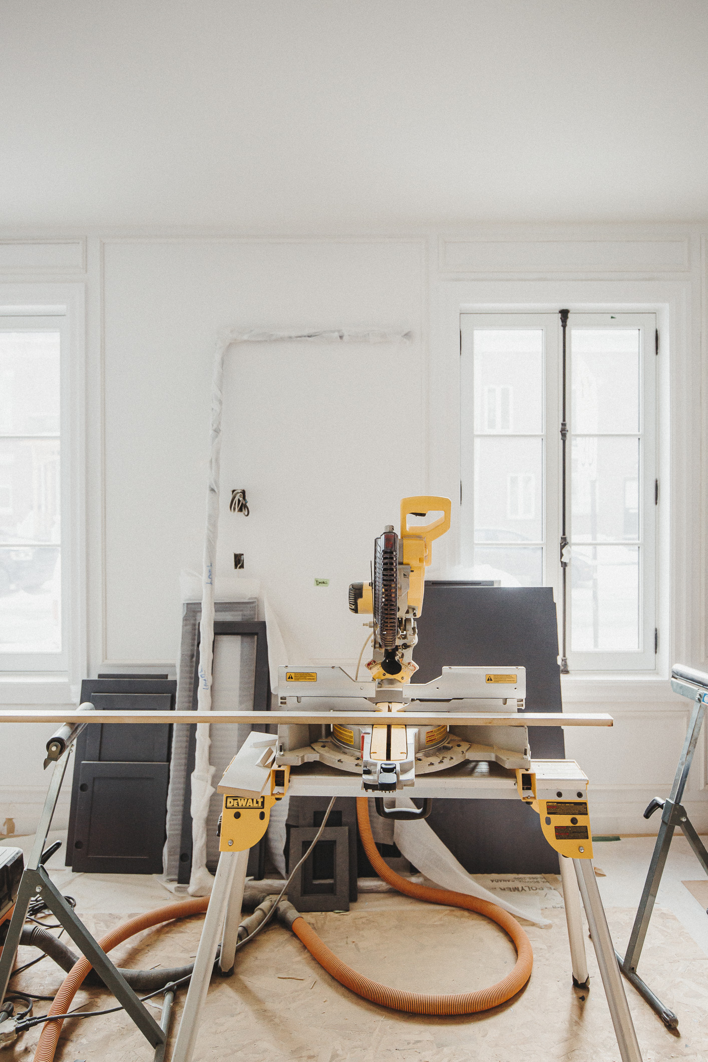 A bright renovation space features a yellow miter saw amid organized tools and plywood, showcasing the potential for transformation.