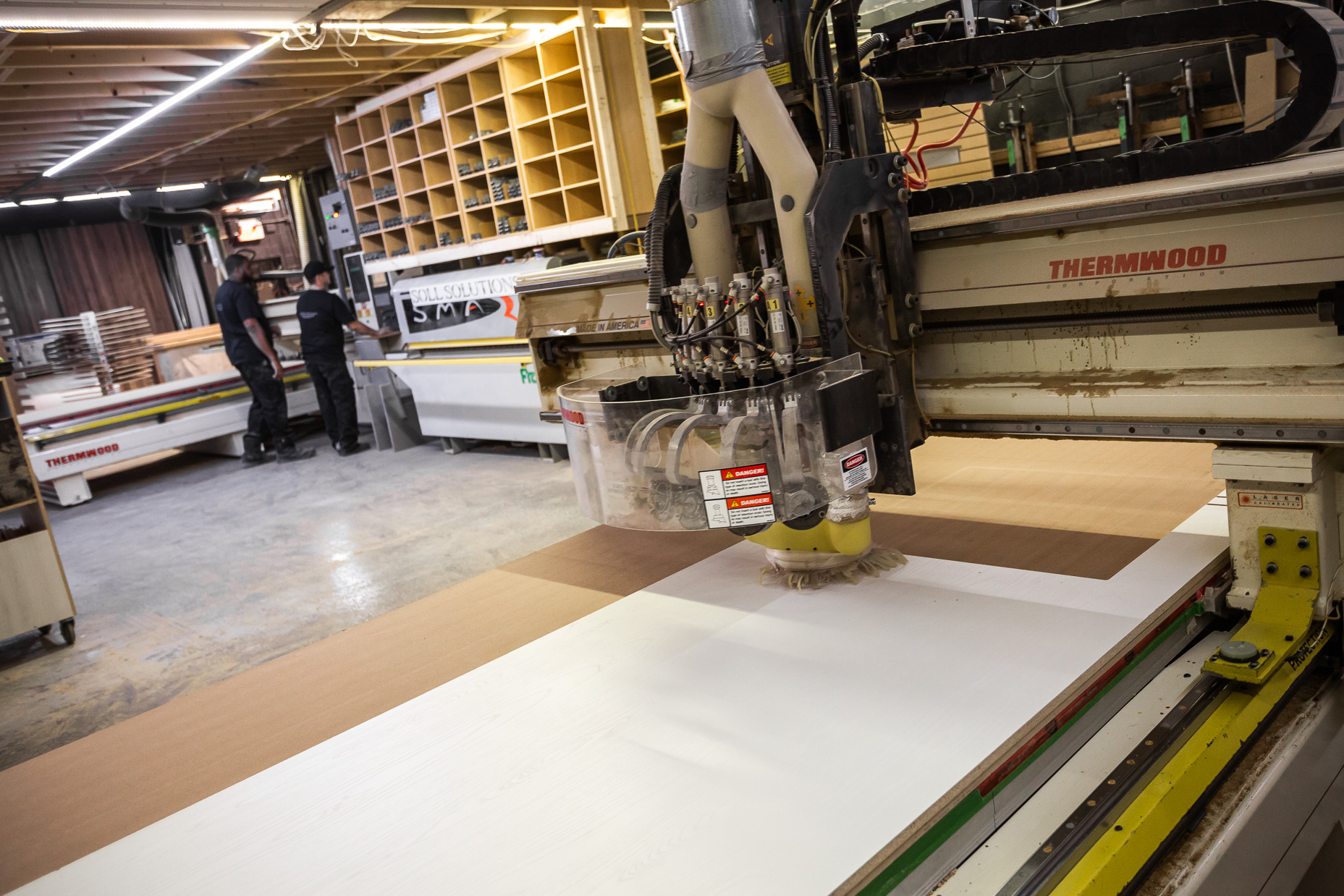 A skilled team collaborates in a modern woodworking shop, utilizing advanced CNC technology for precise craftsmanship and efficient production.