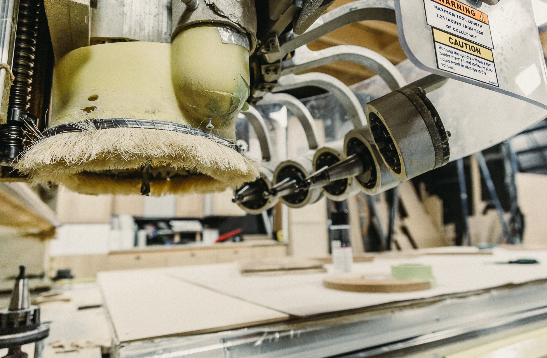 Intricate details of a CNC router tool in a busy woodworking shop showcase technology blending with craftsmanship for precision and finishing.
