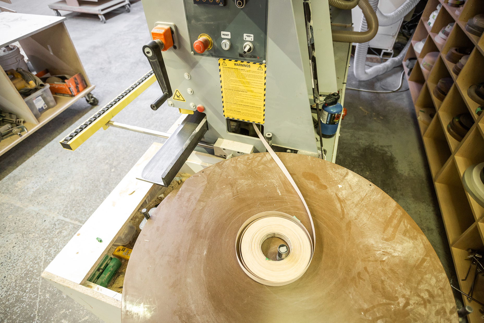 A woodworking lathe operates a spinning wooden disk, highlighting precision craftsmanship in an organized workshop.