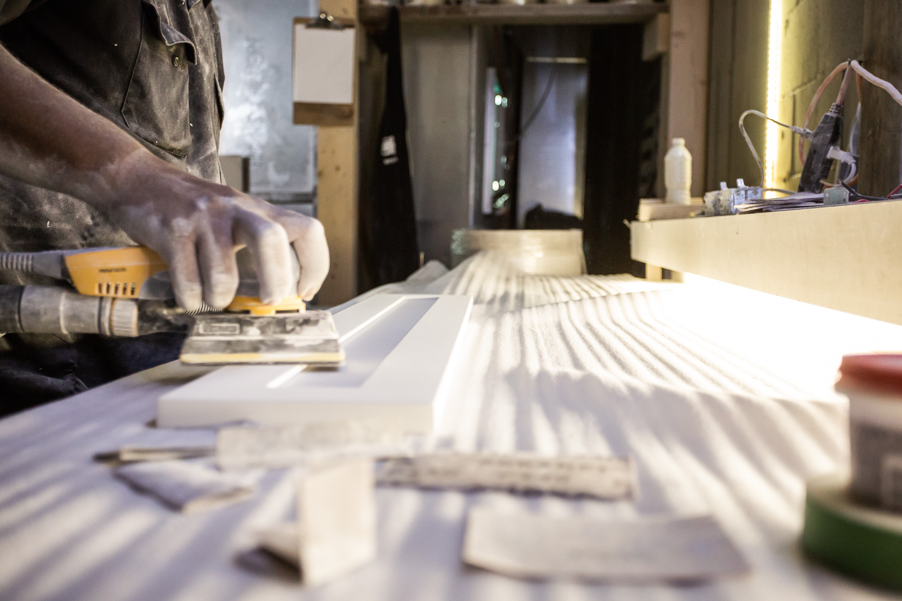 A craftsman skillfully works with a power sander in a well-organized workshop, surrounded by tools and materials that inspire creativity.