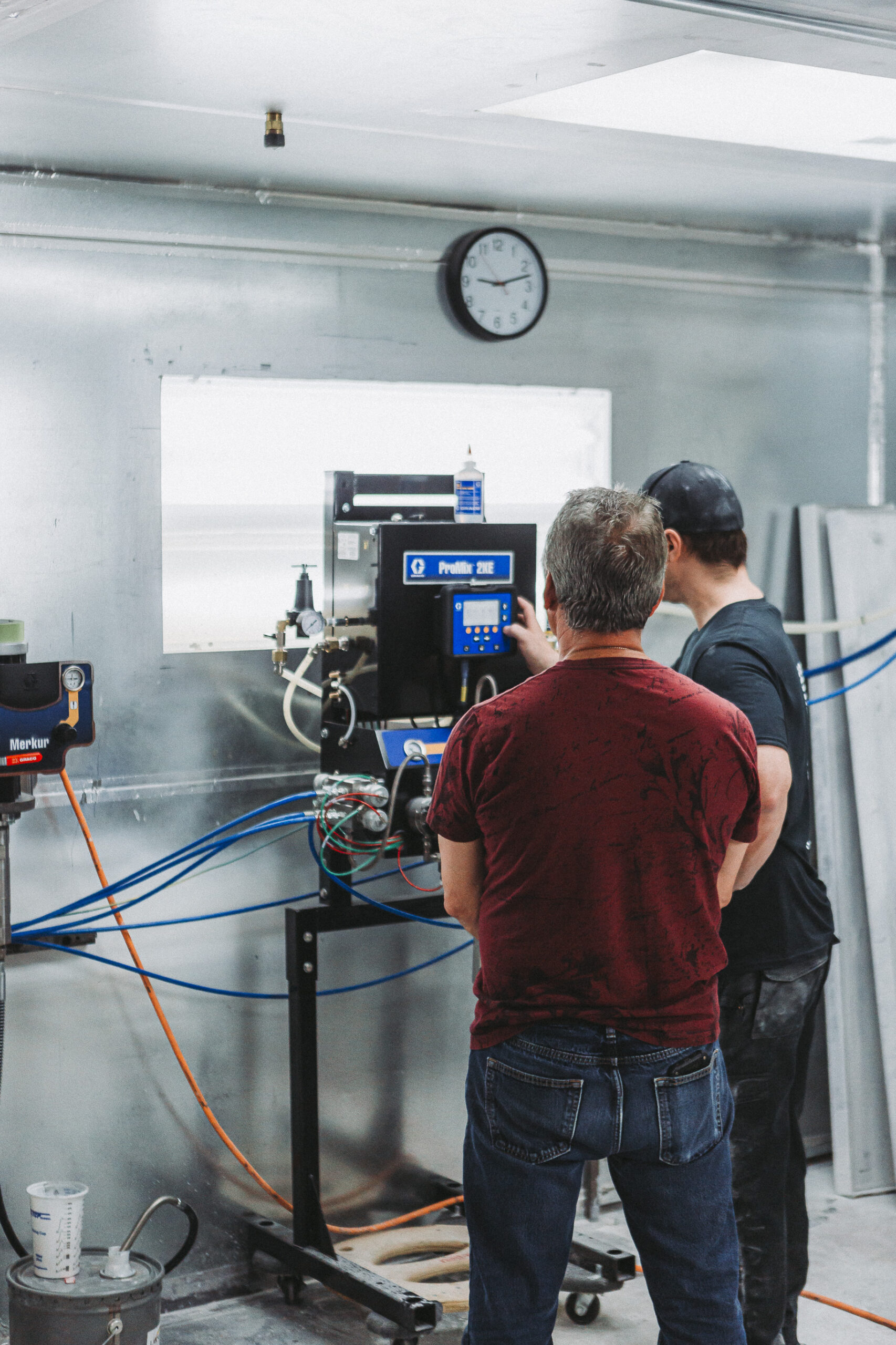 Two men collaborate on a complex machine in a bright and organized workshop, highlighting teamwork and technical innovation.