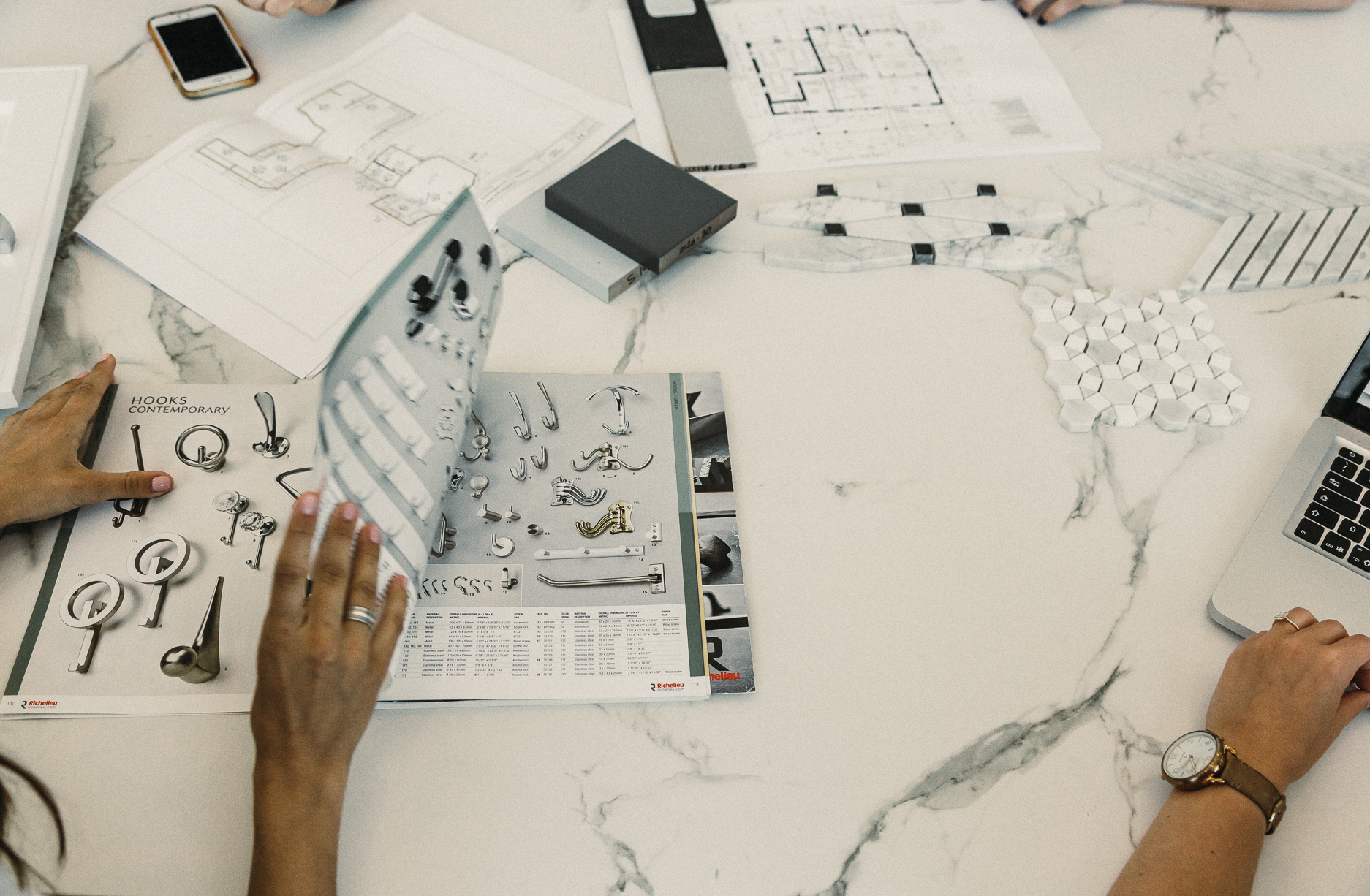Creative collaboration thrives at a modern marble table, filled with documents and digital tools for innovative discussions and design work.