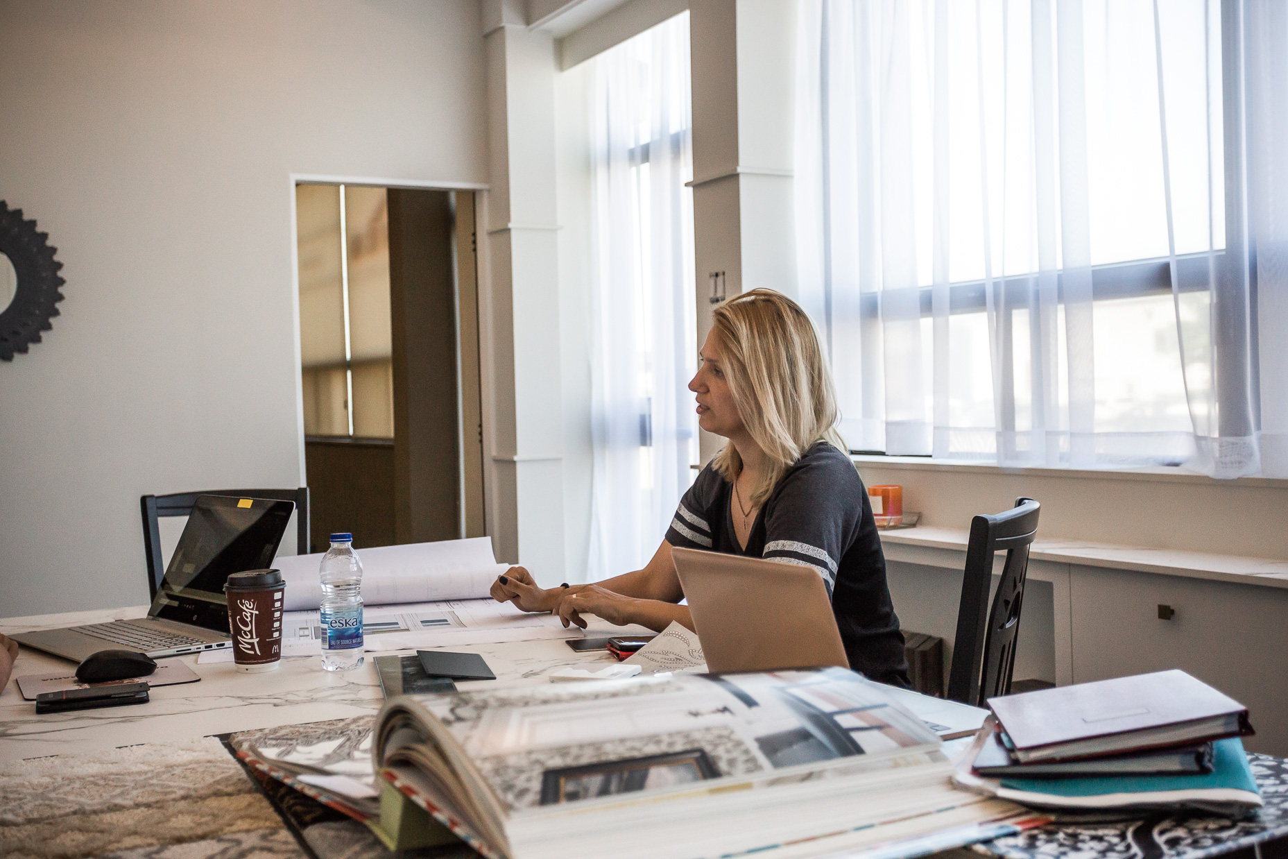 A focused woman works in a bright, inspiring workspace filled with natural light and rustic charm.