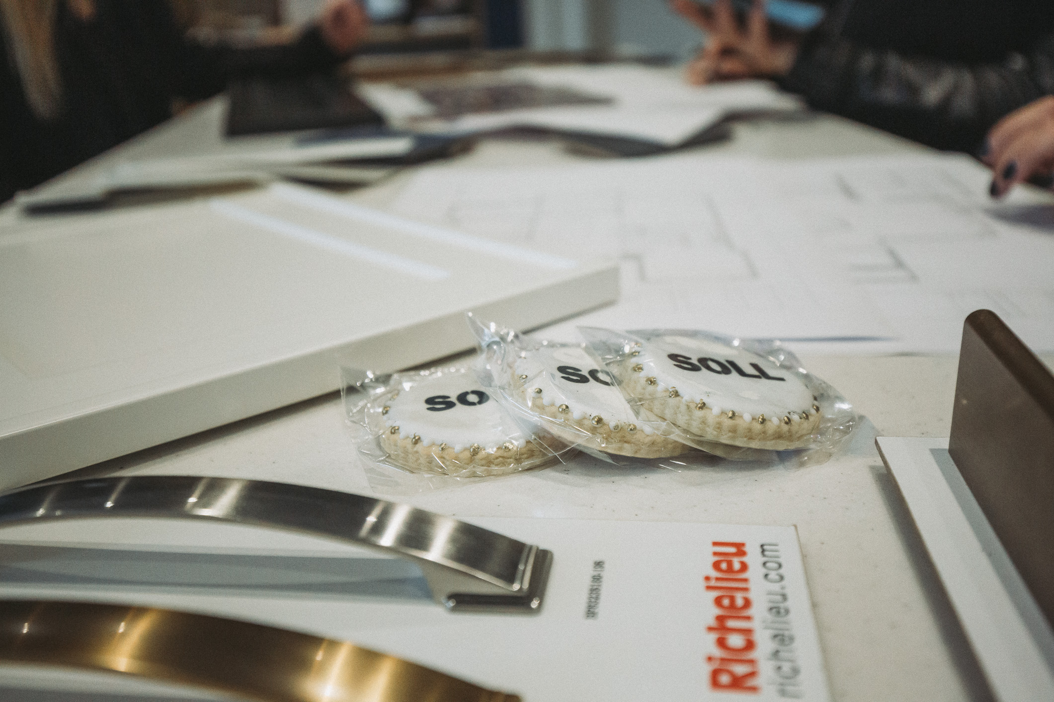 A collaborative design meeting features blueprints, hardware samples, and cookies celebrating a significant 50th milestone.