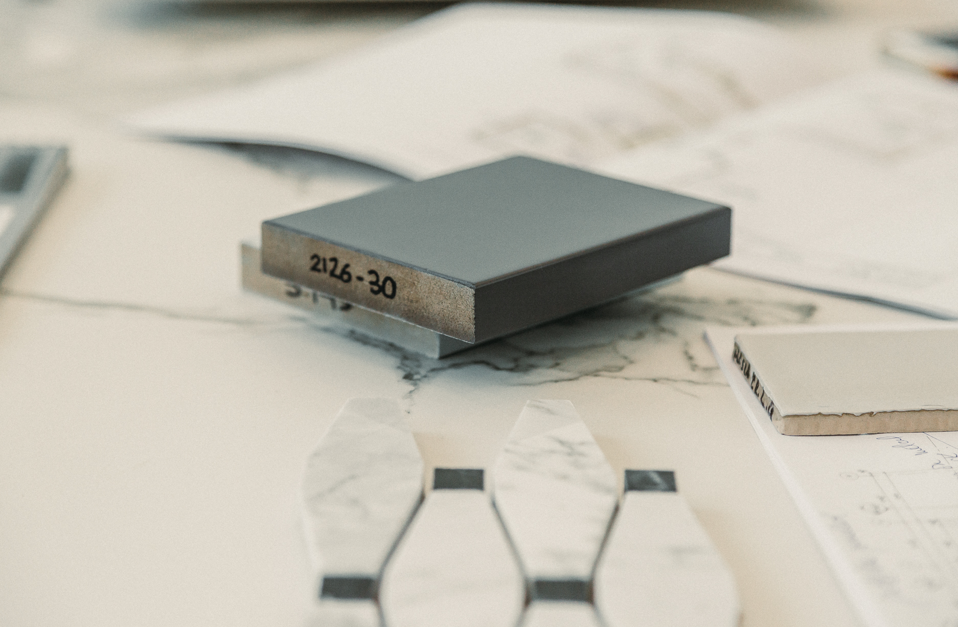 A modern design workspace features a gray block and elegant marble samples surrounded by sketches, capturing creativity and meticulous planning.