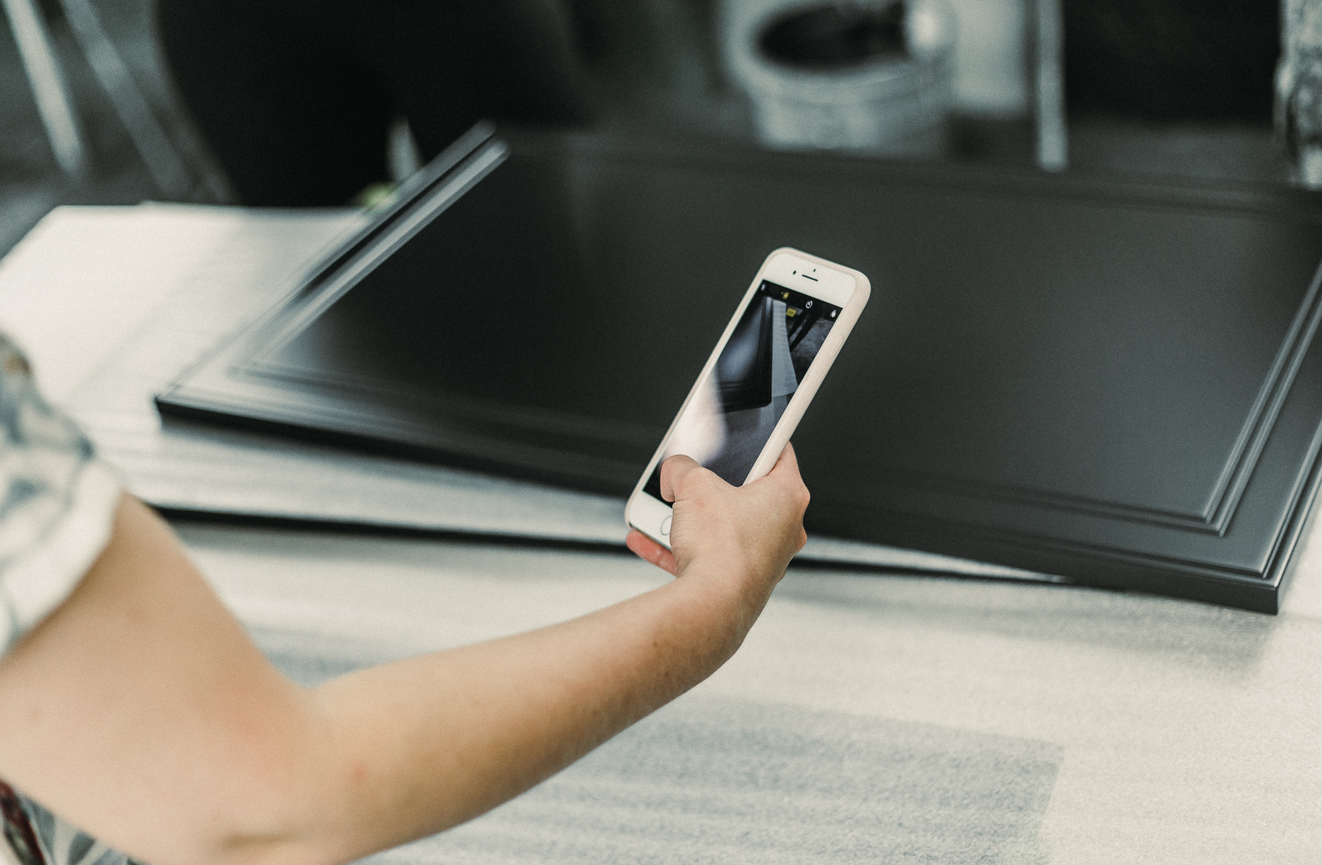 A designer captures the elegance of a polished surface with a smartphone in a creative workspace.